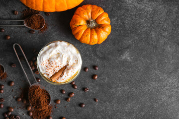 Glass of pumpkin cappuccino on dark background