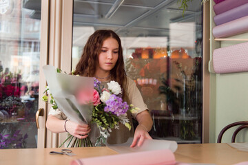 Young woman florist makes a bouquet at workplace, small business concept, lifestyle