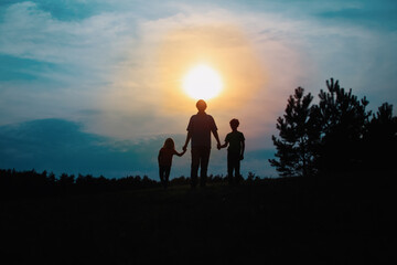 Fototapeta premium father with son and daughter walk at sunset