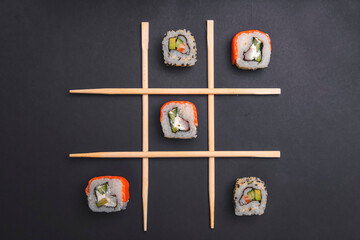 Tic tac toe game with sushi on dark black background, creative concept sushi rolls. Banner, playing tic tac toe game.