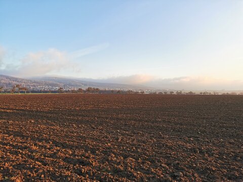 Braunes Ackerland mit der Ortschaft Mönchberg im Spessart im Hintergrund