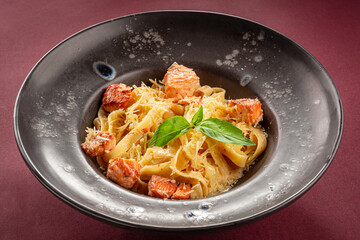Pasta with salmon and leaf on burgundy background. 

