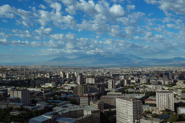 Cityscape of Yerevan city with buildings rooftops under blue sky with clouds in Armenia 