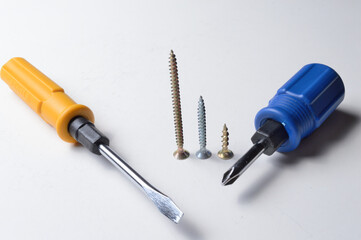 two different screwdrivers and several screws on a white background. close-up.