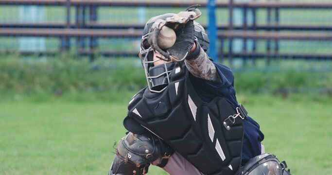 Portrait of a boy baseball player on a blurry background, the catcher in protective gear catches a flying fastball to the glove, 4k slow motion.