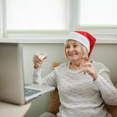 Online celebration. Woman with glass of wine celebrating Christmas with her family via internet