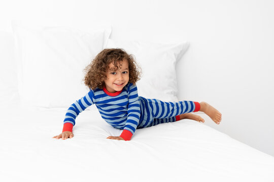 Smiling toddler boy playing on white bed