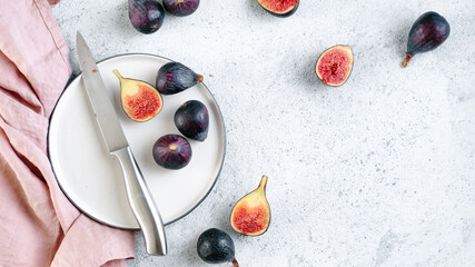 Half and whole figs on gray cement or stone background. Ripe violet figs with copy space for text. Top view or flat lay. Horizontal banner