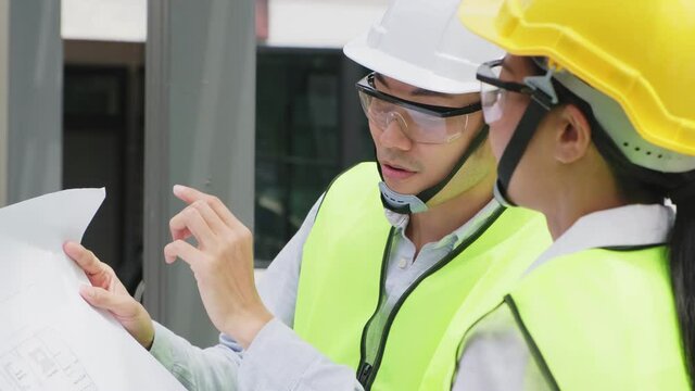 Asian young engineer man explaining job on drawing to female worker.