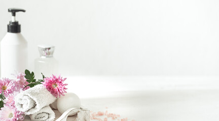 Spa composition with body care products and flowers on a light background copy space.