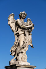 Fototapeta na wymiar Angel with the Crown of Thorns on Ponte Sant Angelo bridge in Rome, Italy. Marble sculpture from 17th century by Naldini, design of Bernini