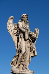 Fototapeta na wymiar Angel with the Garment and Dice statue on Ponte Sant Angelo bridge in Rome, Italy. Marble sculpture from 17th century by Paolo Naldini