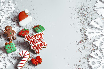 Christmas light blue background with bright gingerbread, paper snowflakes top view copy space.