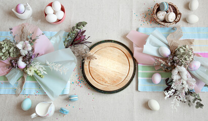 Fototapeta na wymiar Easter dining table setting and decor with a wooden element in the center top view.