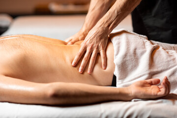 Obraz na płótnie Canvas Man receiving a deep massage on his back from professional therapist at luxury spa salon