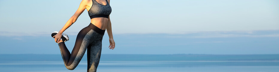 Female posing in sportswear on sky background. The middle part of the body.