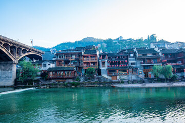 the river, the boat, stone bridge and the old houses at ancient phoenix town in the morning at...