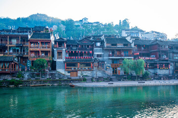 the river, the boat, stone bridge and the old houses at ancient phoenix town in the morning at...