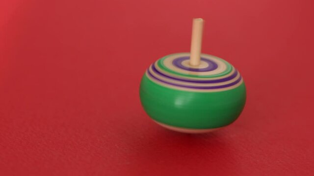 Colorful wooden spinning top on red background.