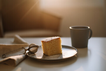 Homemade fresh cake with icing sugar. Table with a piece of cake and cup of coffee or tea