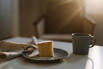 Homemade fresh cake with icing sugar. Table with a piece of cake and cup of coffee or tea