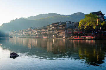 the river, the boat, stone bridge and the old houses at ancient phoenix town in the morning at...