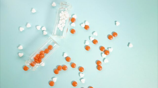 White and orange tablets are collected in glass jars. Stop motion video.