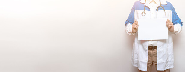 Young doctor holds a blank piece of white paper in his hands on a white background. Isolated. Christmas and New Year concept. Portrait. Copy space. Place for text
