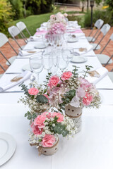Wedding table decorated with bouquet of pink flowers and wine glasses.