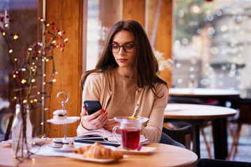 Beautiful woman text messaging while sitting in the cafe
