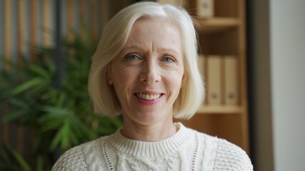 Portrait of a beautiful elderly woman with gray hair, she smiles standing at home