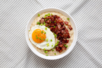 Homemade Cheesy Bacon Savory Oatmeal Bowl on cloth, overhead view. Top view, from above, flat lay.