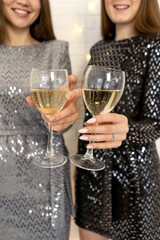 Two beautiful elegant women celebrate christmas and new year with champagne. Best friends wearing shiny gray and black stylish evening dress. Champagne glasses close-up.