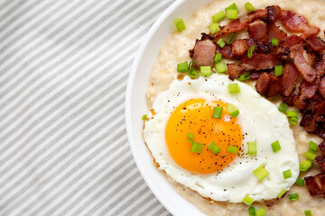 Homemade Cheesy Bacon Savory Oatmeal Bowl on cloth, top view. Overhead, from above, flat lay. Space for text.