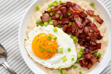 Homemade Cheesy Bacon Savory Oatmeal Bowl on cloth, top view. Overhead, from above, flat lay. Close-up.