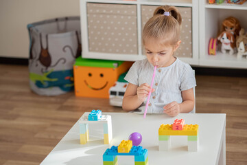 Little girl enjoying game straw maze. Great activity for building oral motor skills at home.