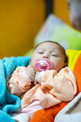 Blurry Shot of Asian Baby Girl with Pacifier in her mouth while she is calm and falling asleep