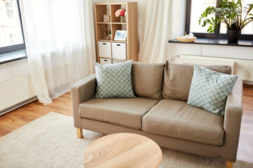 comfort, furniture and interior concept - sofa with cushions at cozy home living room