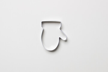 cookie cutter in form of glove on white colored paper background. isolated. close up. mock up