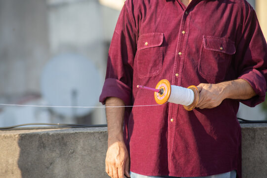 Slow Motion Shot Of Man Holding A Charki Phirki Thread Spool In The Crook Of His Elbow And Winding It With The Other Hand To Ensure Taughtness For The Famed Kite Fighting Festival Of Makar Sankranti 