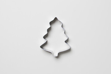 cookie cutter in form ofchristmas tree on white colored paper background. isolated. close up. mock...