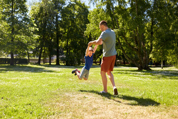 family, fatherhood and people concept - happy father with little son playing in summer park