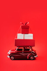 Red toy car with Christmas presents on red isolated background.