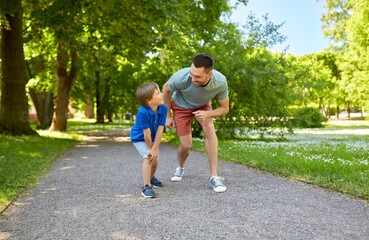 Fototapeta premium family, fatherhood and people concept - happy father and little son compete in running at summer park