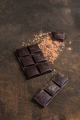 Dark chocolate bar on dark wooden texture background