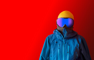 Front of a man in skiing / snowboarding outerwear isolated over a contrast red background with copy space for additional content. 