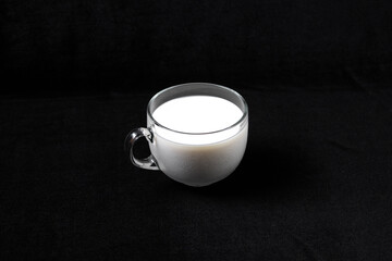 Mug with milk on a dark black background.