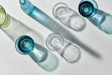 glassware concept - different glasses and bottles dropping shadows on white surface