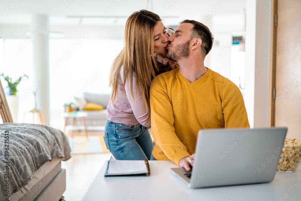 Poster Mother playing with her kid while dad is working on a laptop.