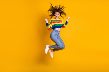 Fototapeta na wymiar Full length photo of lucky jumping woman dressed casual colorful sweatshirt arms hands fists isolated yellow color background